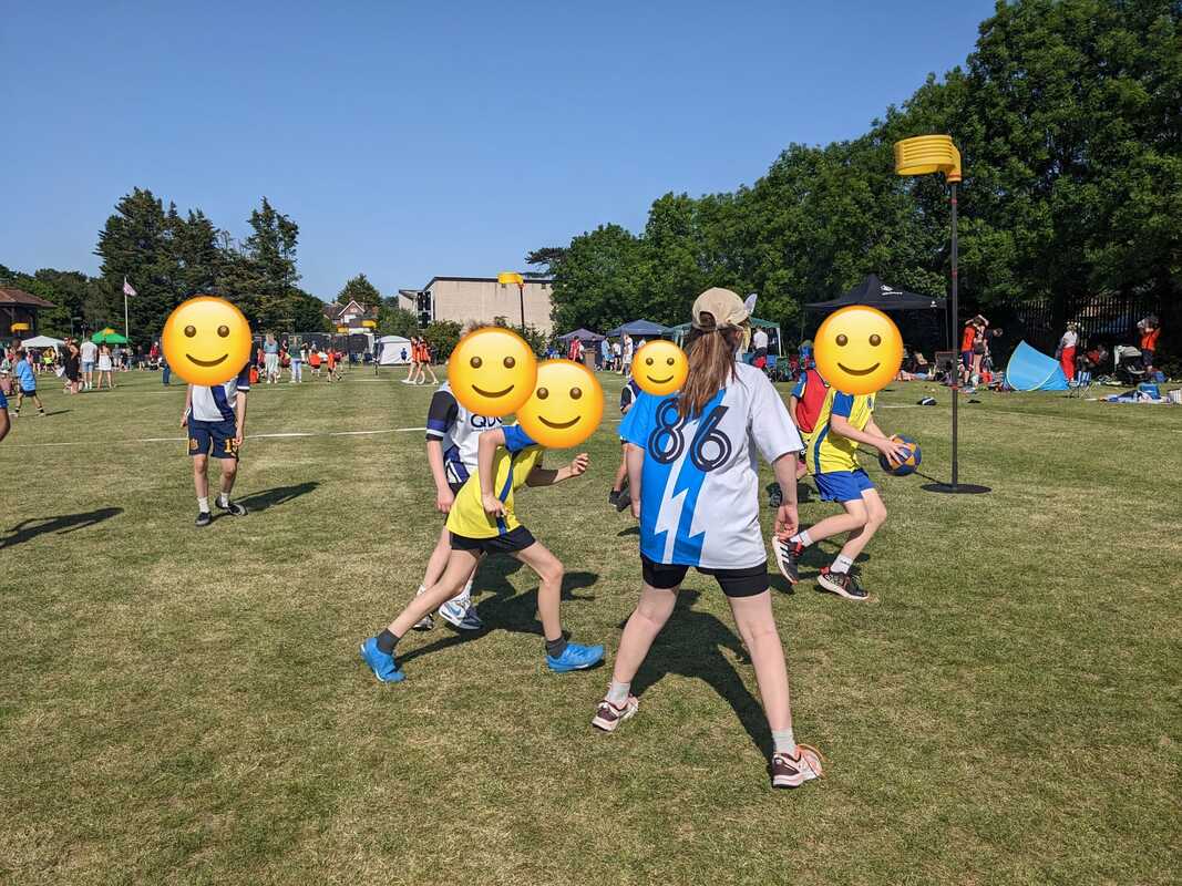 A player in a blue-and-white 86 shirt referees some children playing korfball